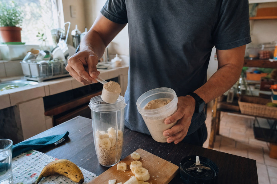 Persona preparando un batido con proteína, avena y plátano en una cocina cotidiana